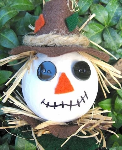 Scarecrow craft ornament with green leaves in the background