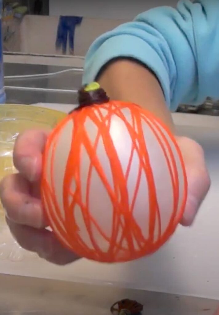 balloon wrapped with orange embroidery floss and a brown floss topper to make a string pumpkin craft