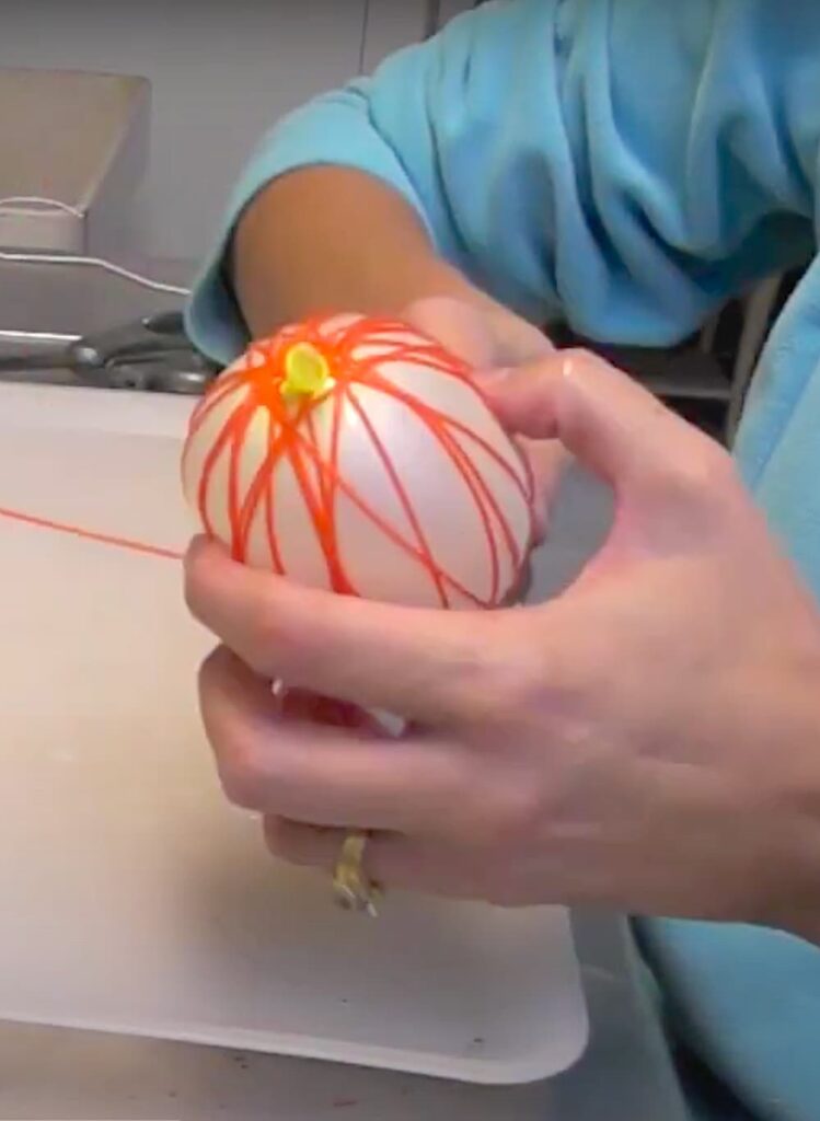 winding orange string around the balloon to make a pumpkin craft