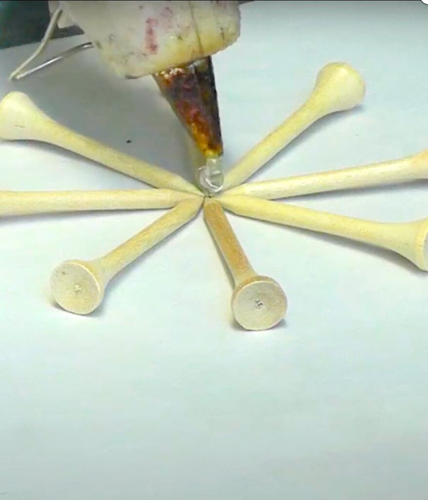 How to make a snowflake with wood golf tees arranged in the shape of a snowflake and dripping hot glue in the center to keep it together