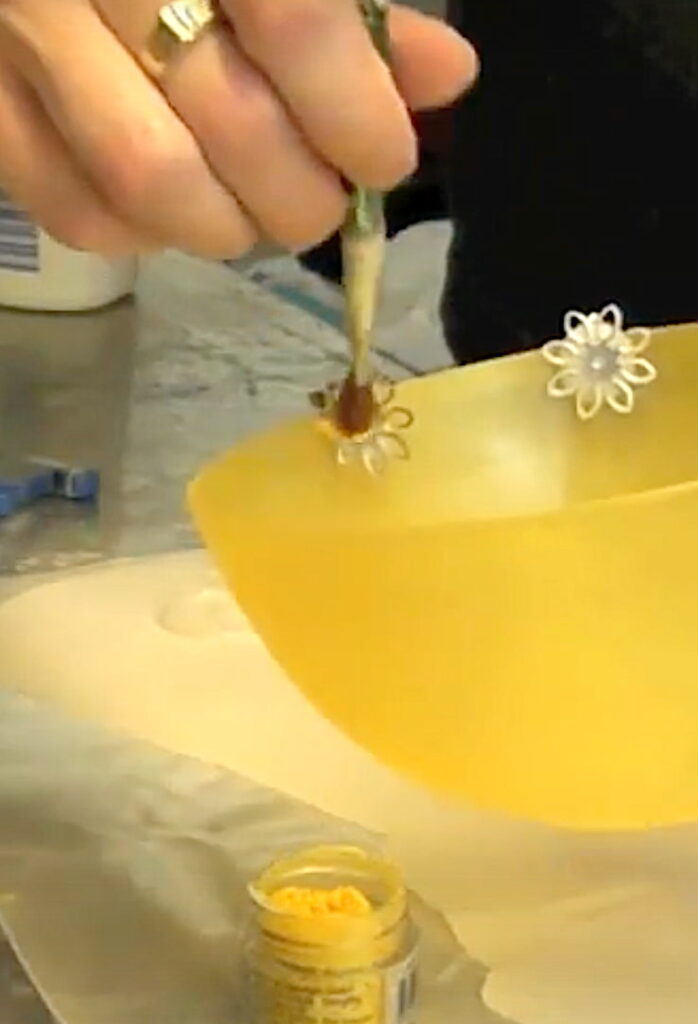 Brushing yellow pigment powder onto sunburst earrings