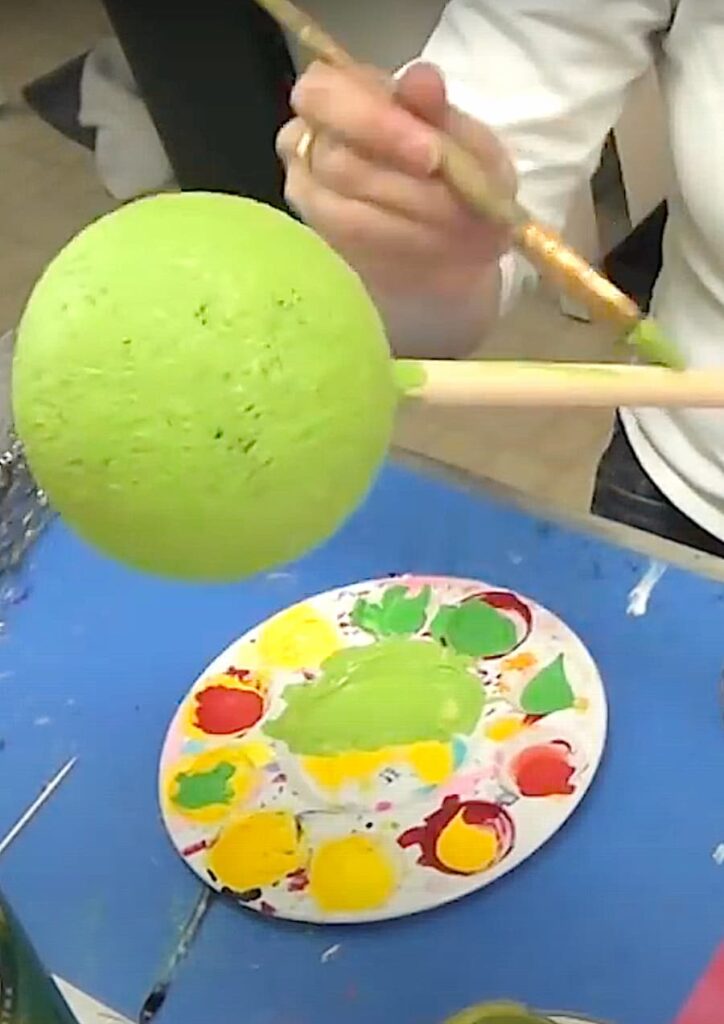 Painting the styrofoam ball and stem with green paint for the dandelion wish flower