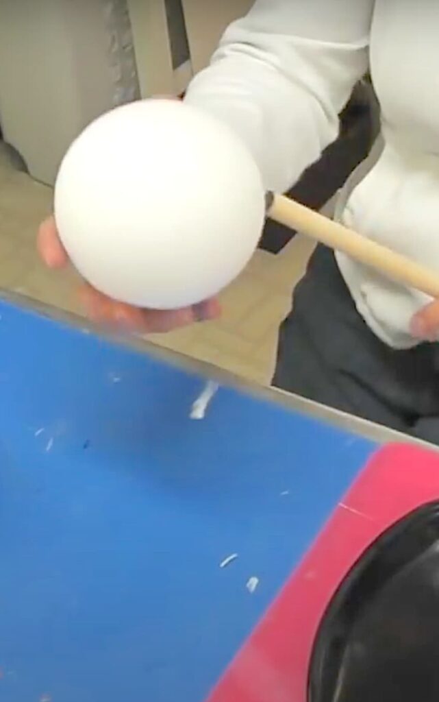 Inserting a dowel rod into a styrofoam ball