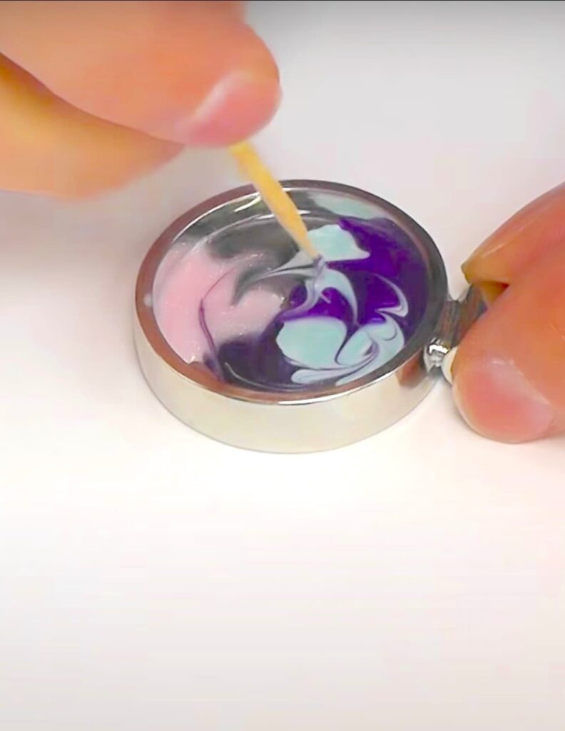 Using a toothpick to swirl nail polish colors together in bezel copy