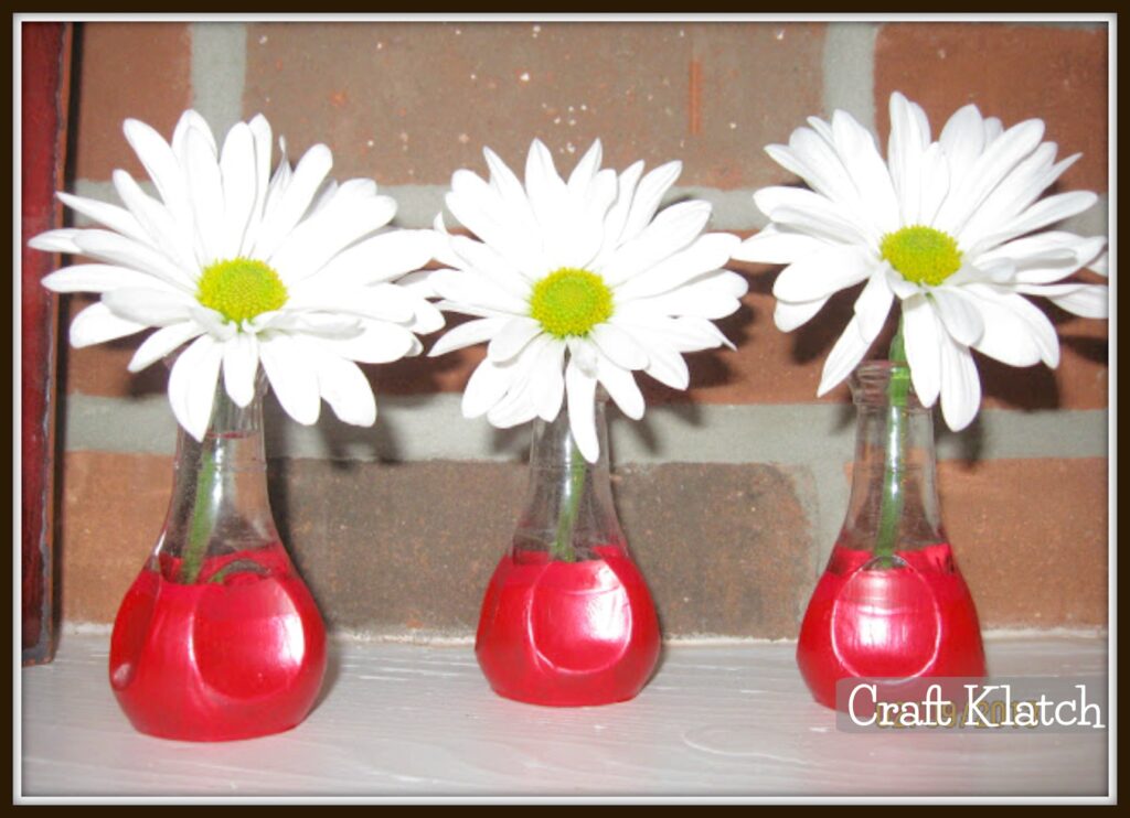 Red painted bud vases with daisies