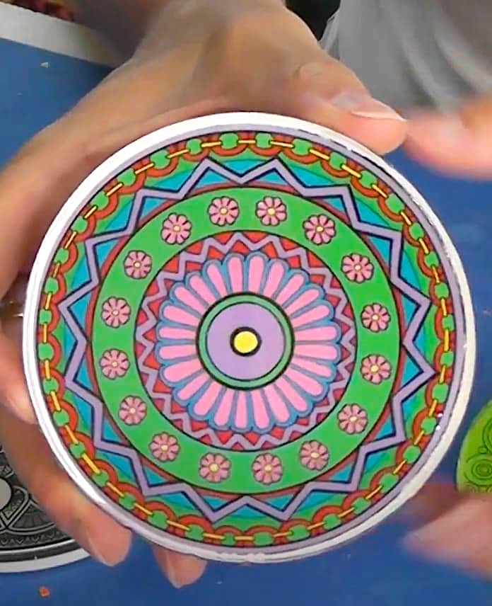 Holding up colorful mandala art coaster