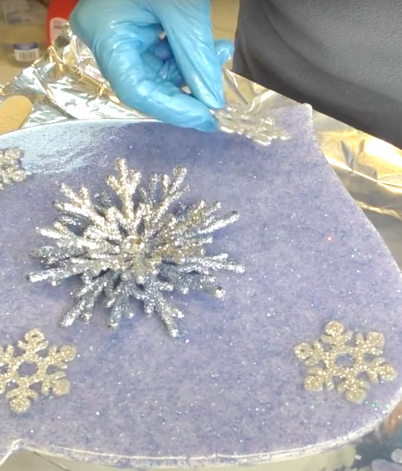 Placing silver ornament on the snowflake craft ornament