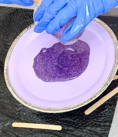 Pouring purple glitter resin onto the purple serving tray