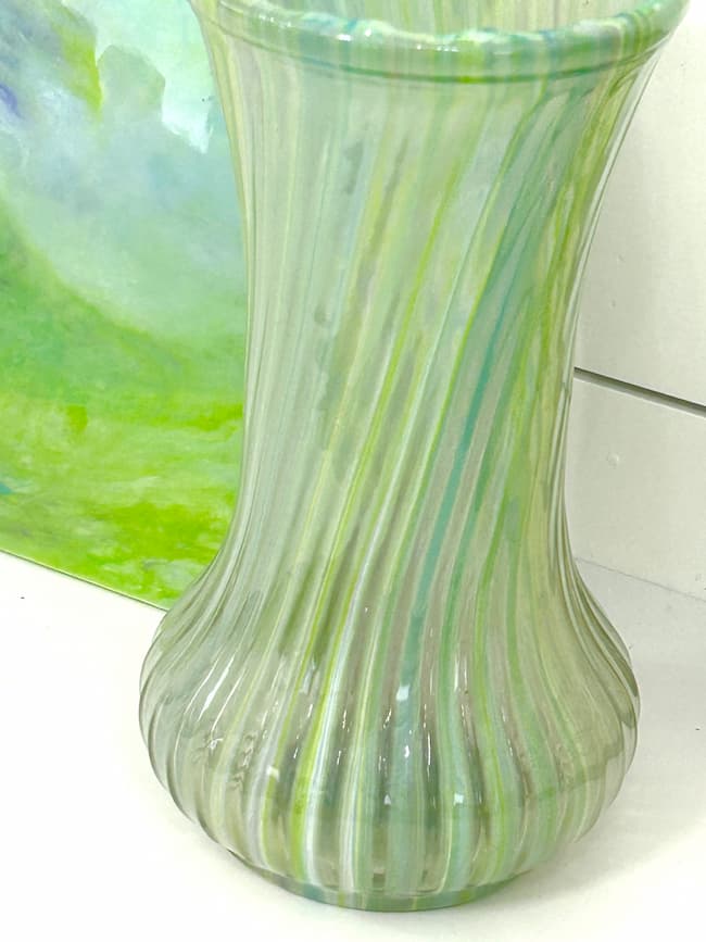 Resin flower vase with textures and green and blue coloring with canvas in the background