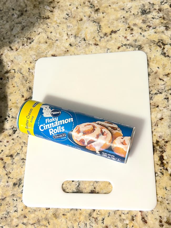 Roll of Pillbury cinnamon rolls on a white cutting board