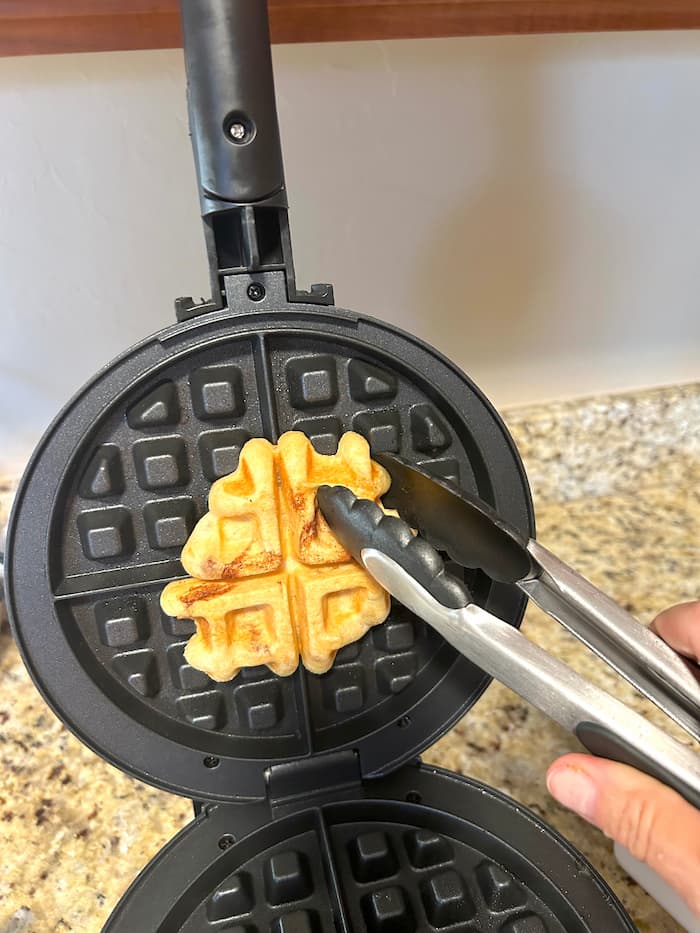 Removing a cinnamon roll from a waffle maker with tongs