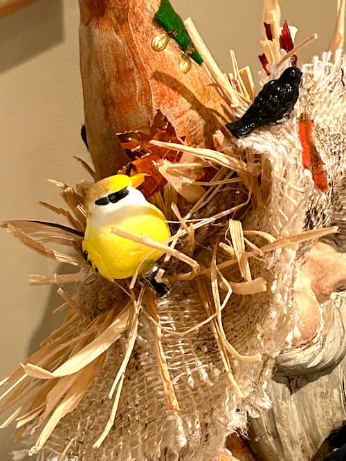 birds nestled in the straw hat of the scarecrow gnome