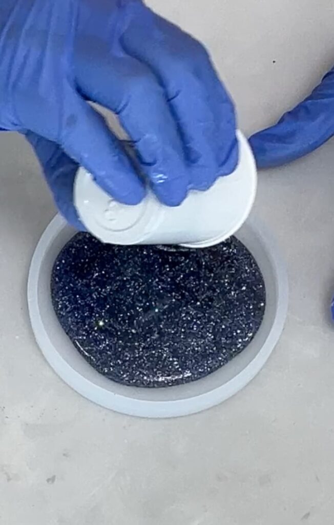 Pouring glittered resin into coaster mold