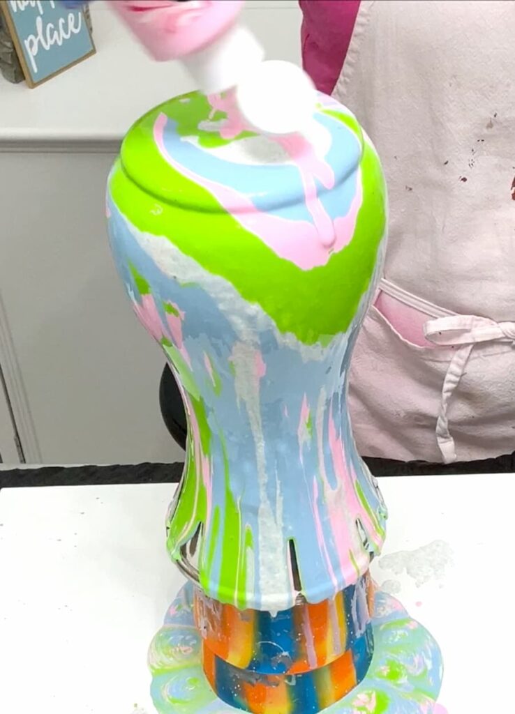 Doing acrylic paint pour with green, pink and blue paints to turn it into a pretty vase