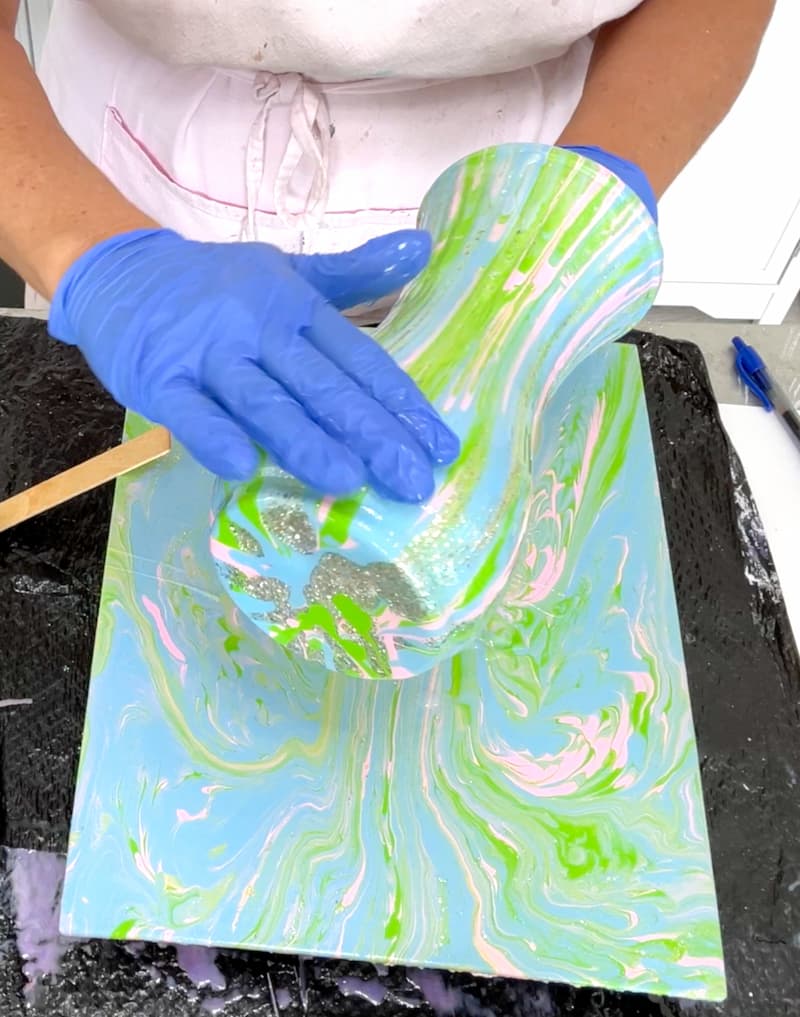 Using gloved hands to move resin all over the pretty vase