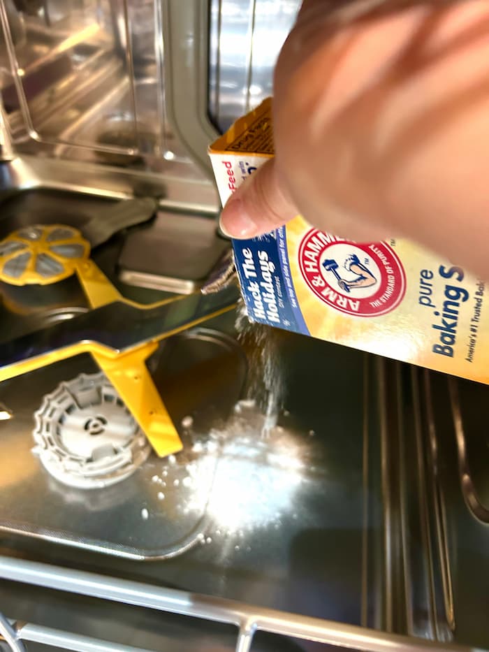 Pouring baking soda in dishwasher bottom