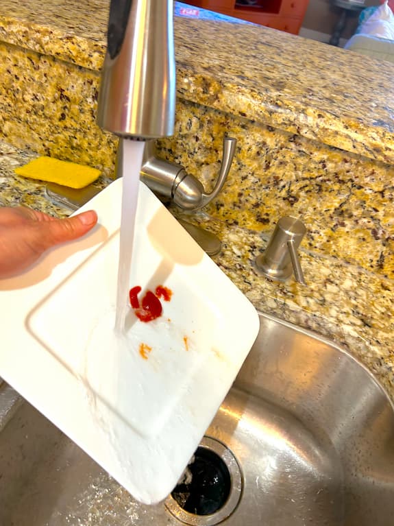 Rinsing white dish under sink