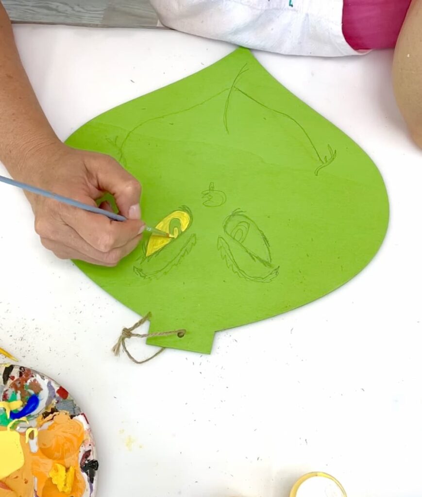 Painting the Grinch eyes yellow for the How to make the grinch ornament project