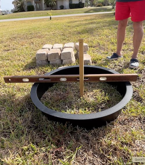 using a level to make sure the ground for fire pit kit is flat when figuring out how to build a firepit